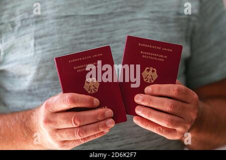 Primo piano di due nuovi passaporti tedeschi in mano di un uomo Foto Stock