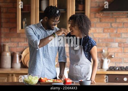 Sorridente giovane coppia biraciale divertirsi a cucinare a casa Foto Stock