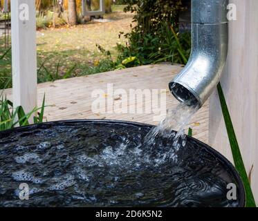L'acqua viene scaricata dal tubo di scarico in un contenitore metallico Foto Stock
