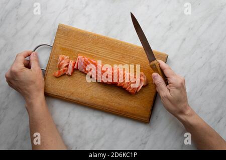 donna tritato salmone salato su tavola da cucina, vista dall'alto Foto Stock