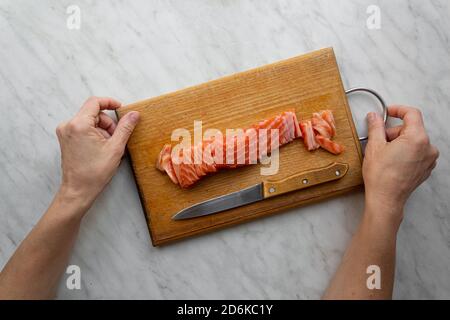 donna tritato salmone salato su tavola da cucina, vista dall'alto Foto Stock