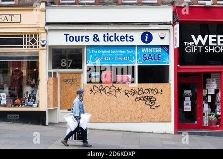 L'uomo che indossa la maschera per lo shopping a Edimburgo cammina oltre il tour aziendale imbarcato sul Royal Mile durante la pandemia del coronavirus, Scozia Foto Stock