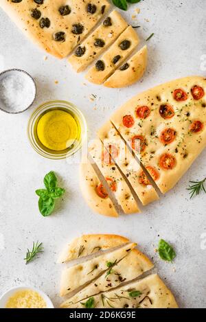 Focaccia con vari ripieno di verdure. Focaccia appena sfornata con pomodori, olive, aglio ed erbe, vista dall'alto. Foto Stock