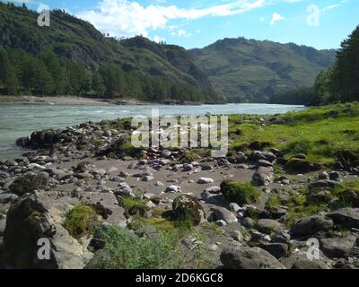 Il fiume infuria alte montagne scure il passo di montagna Altai nella valle verde sulle rive Foto Stock