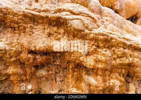 L'acqua proveniente dalle sorgenti minerali scorre attraverso il pendio calcareo della montagna accanto alla strada militare georgiana. Foto Stock