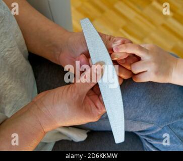 Dettaglio delle mani di una donna che limano le unghie del piede un bambino Foto Stock