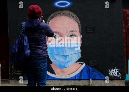 Giovane uomo scattando la foto del murale in High Street, Manchester. Nurse Debra Williams come angelo di AKSE. Nuova arte di strada che celebra NHS lei Foto Stock