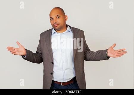 Disgruntato teso e preoccupato giovane uomo d'affari afro-americano con un'espressione cinica e arrabbiata si allarga le mani in un gesto impotente che diffonde le sue palme, come se non sapesse cosa fare. Foto Stock