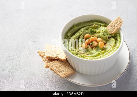 hummus all'avocado in ciotola bianca con ceci, prezzemolo, spezie e cracker di riso Foto Stock