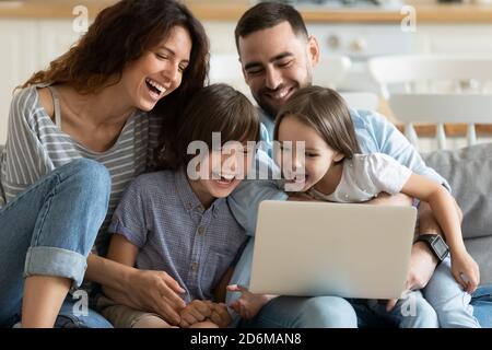 I genitori sono molto contenti con il figlio e la figlia che usano il computer portatile insieme Foto Stock