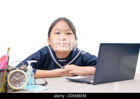 Felice ragazza cute che guarda i video in streaming online sul suo laptop a casa isolato su bianco. Homeschooling, apprendimento a distanza e nuovo concetto normale Foto Stock