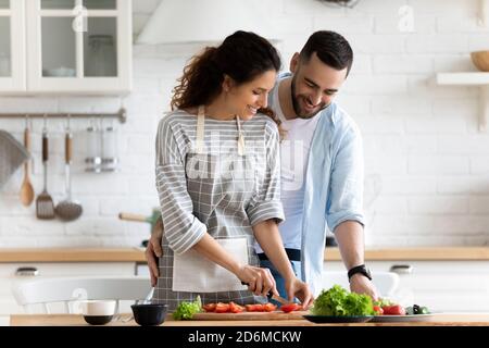 Felice coppia amorosa preparare la cena in cucina insieme, abbracciando Foto Stock