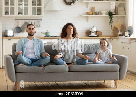 Giovane madre pacifica e padre con piccola figlia che pratica yoga Foto Stock