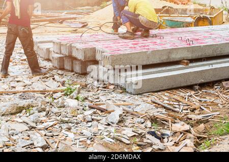 lavoratore spostare pali di cemento palo pilastri su terra da imbracatura in cantiere Foto Stock