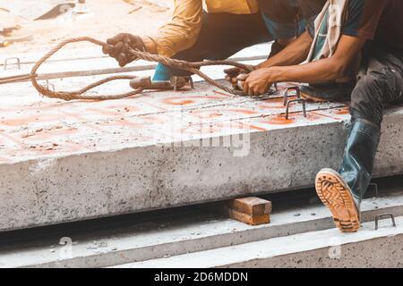 lavoratore spostare pali di cemento palo pilastri su terra da imbracatura in cantiere Foto Stock