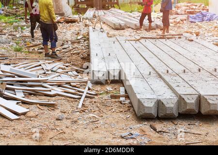 lavoratore spostare pali di cemento palo pilastri su terra da imbracatura in cantiere Foto Stock