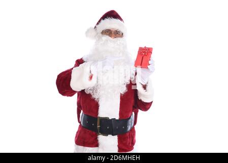 Uomo anziano che indossa un costume tradizionale di Babbo Natale che tiene un piccolo regalo di carta rossa avvolto in una mano e che lo indica con l'altra. Isolato o Foto Stock