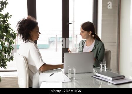 Sorridente giovane razza mista diverse donne d'affari che parlano in ufficio. Foto Stock