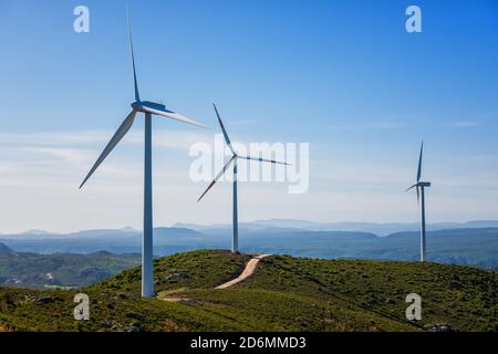 Turbine eoliche su un bellissimo cielo blu in un parco eolico di montagna in Sardegna. Concetto di energia rinnovabile, generazione di energia verde. Industria energetica. Foto Stock