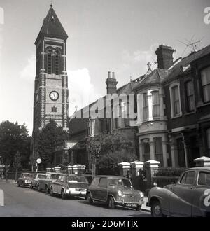 Anni '70, storica, Londra sud-orientale, strada suburbana con auto dell'epoca parcheggiata e torre della chiesa con orologio. Foto Stock