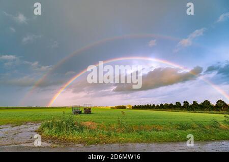 Doppio arcobaleno luminoso e colorato su un paesaggio verde Foto Stock