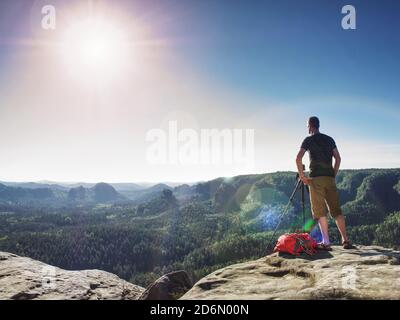 Soggiorno turistico a macchina fotografica su treppiede, guardando nel paesaggio e pensare. L'uomo ascolta il suono della natura pura. Foto Stock