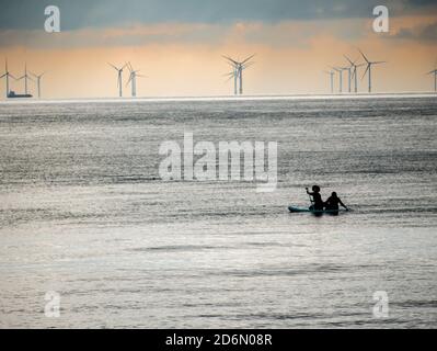 Canoista tutto in mare passando turbine eoliche Foto Stock