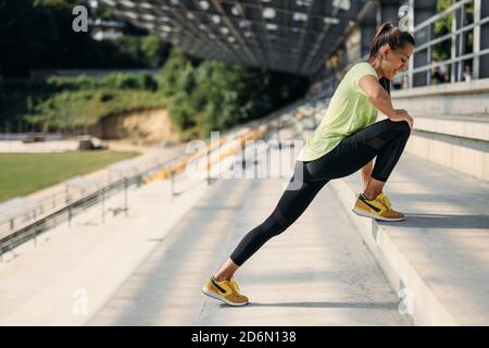 Vista laterale delle gambe che si allungano per donna fitness sulle scale Foto Stock