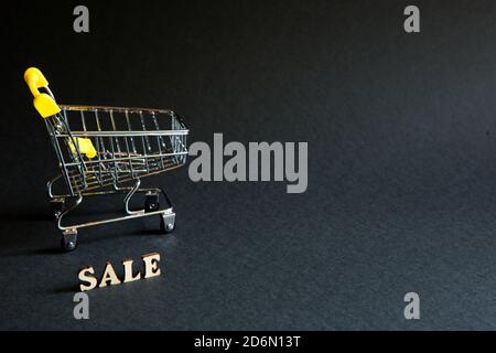 Carrello e l'iscrizione 'vale' su sfondo nero. Black Friday, sconti, vendita, shopping, segno di interesse. Spazio per il testo Foto Stock