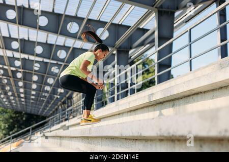 Donna in forma attraente che fa esercizi sportivi sulle scale Foto Stock
