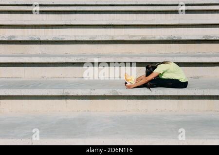 Giovane donna flessibile che allunga il corpo sui gradini Foto Stock