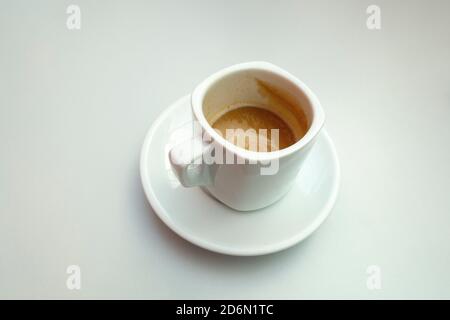 Colpo isolato di una mezza tazza piena di caffè con latte su sfondo bianco Foto Stock