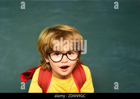 Istruzione. I bambini si preparano per la scuola. Concetto di apprendimento. Primo giorno di scuola. Gli studenti sorridenti che disegnano alla scrivania. Scuola bambini contro il verde Foto Stock