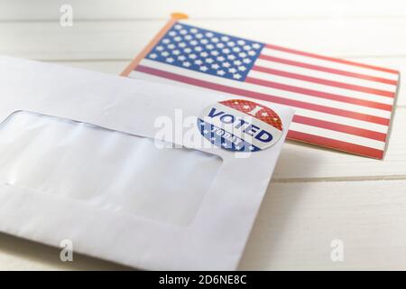 Bandiera USA e busta contenente i documenti di votazione inviati per posta per il voto degli assenti alle elezioni presidenziali Foto Stock