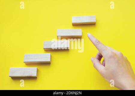 Primo piano mostra mano su legno blocco impilamento come scala. Processo di successo per la crescita del concetto aziendale. Concetto di istruzione, rischio, sviluppo e crescita Foto Stock