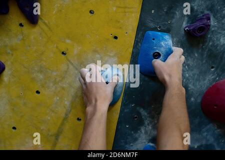 Un primo piano di un mans mani che si tiene su una staffa durante l'arrampicata in montagna al coperto. Foto Stock