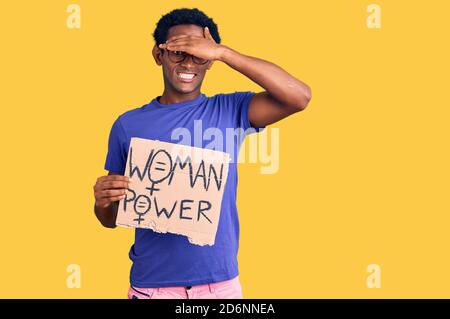 L'uomo africano bello che tiene la bandiera di potere della donna sollecitato e frustrato con la mano sulla testa, sorpreso e faccia arrabbiata Foto Stock