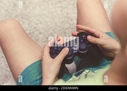 Ragazzo con un gamepad che gioca su una console di gioco. Foto Stock