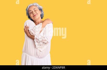 Donna anziana con capelli grigi in stile bohémien che si abbracciano felice e positivo, sorridente sicuro. Auto amore e cura di sé Foto Stock