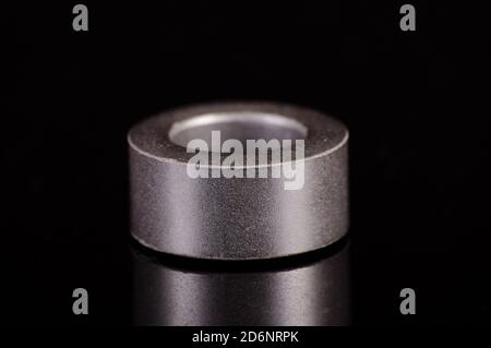 Anello interno in ferrite a forma di toroide isolato su lo sfondo nero riflettente Foto Stock