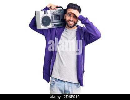 Giovane bell'uomo con barba che ascolta la musica usando il boombox vintage stressato e frustrato con la mano sulla testa, sorpreso e arrabbiato viso Foto Stock