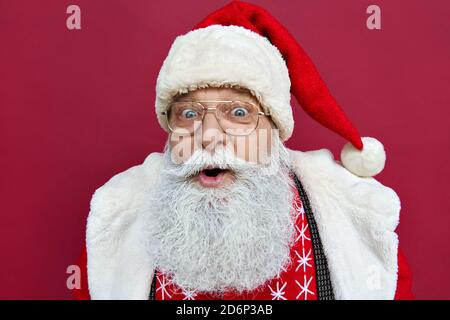 Sorpreso eccitato divertente Babbo Natale indossare costume isolato su sfondo rosso. Foto Stock