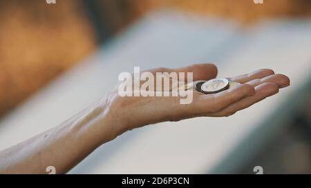 Primo piano, donna senza casa anziana con monete in mano. Concetto di carità e sostegno. Foto di alta qualità Foto Stock