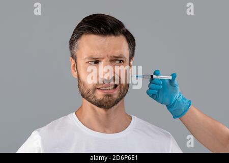 Uomo bearded di mezza età che ottiene l'iniezione di bellezza in salone Foto Stock
