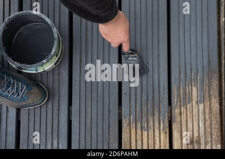 Donne mani Pittura sbiadita vecchio Giardino Decking in legno con Grigio Vernice Foto Stock