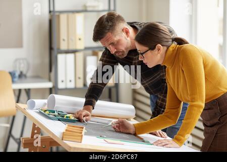 Vista laterale ritratto di due architetti che puntano alla pianta mentre si lavora su progetti sul luogo di lavoro, copia spazio Foto Stock