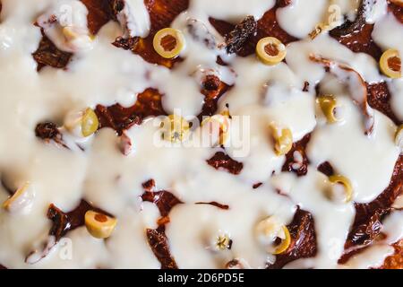 sano concetto di ricette a base di piante, pizza vegana con formaggio di cashew pomodori secchi e olive che sta per andare in forno Foto Stock