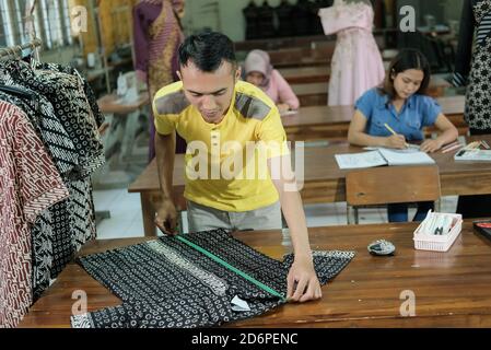 Le sarti asiatiche misurano gli abiti con un righello in base a. regole nella sala di produzione Foto Stock