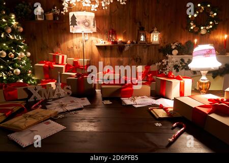 Tavolo da officina Santa con albero di Natale Merry, pile di scatole regalo nella notte di Natale. Foto Stock