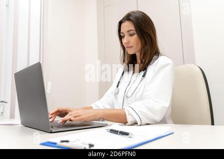 Medico che spiega con il paziente tramite computer portatile, applicazione per la salute mobile. Foto Stock